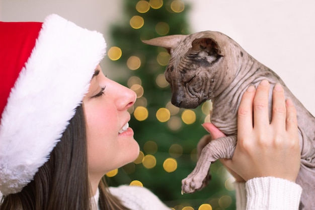 profil d'une jeune femme avec un chat dans ses bras sur le fond d'un arbre de Noël