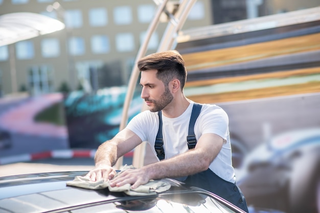 Profil de jeune homme sérieux essuyant la voiture