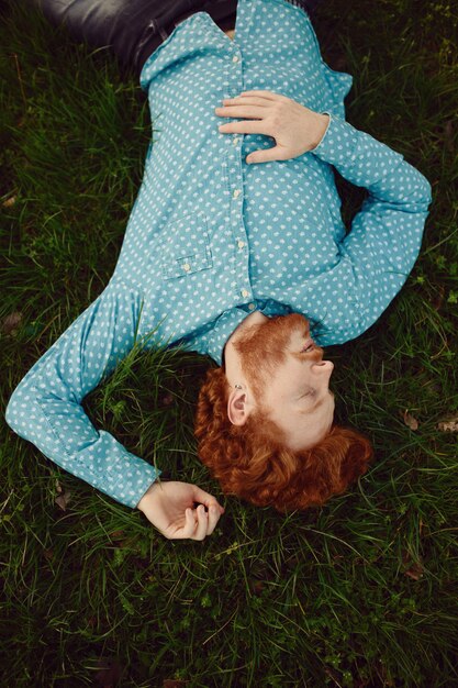 Profil portrait homme rougeâtre bouclé couché sur l'herbe verte