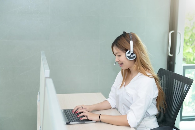 Profil de recherche de belle femme asiatique pour les clients avec le sourire au service de centre d'appelspersonnes thaïlandaisestravail d'affairesjolie fille travaille sur un ordinateur portable au bureau