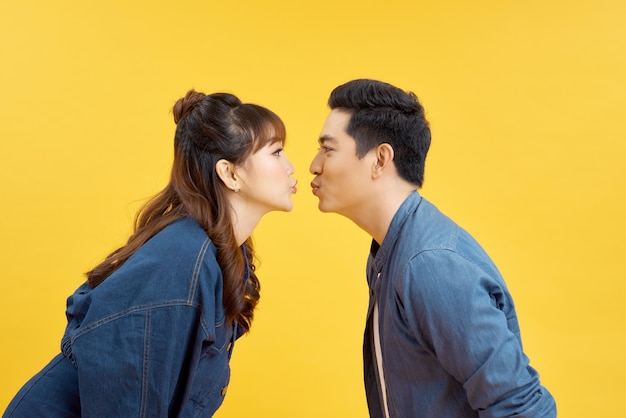 Profils de petite amie et de petit ami se donnant un baiser aérien sur du jaune