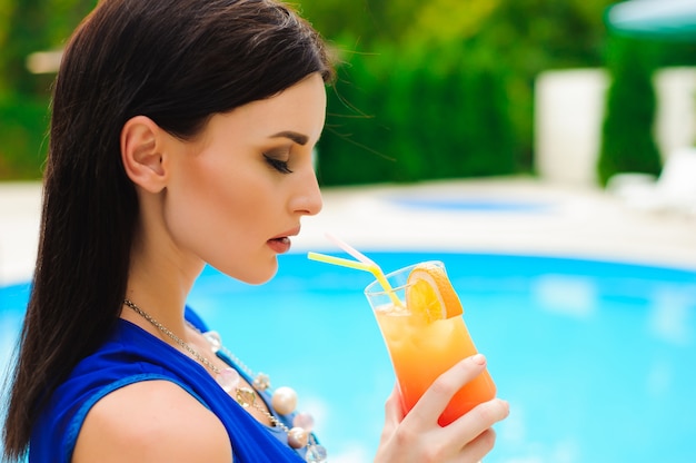 Profitant de l'été. Belle jeune femme buvant un cocktail tout en vous relaxant près de la piscine.