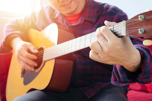 Profitant de temps insouciants à la maison Heureux jeune homme jouant de la guitare