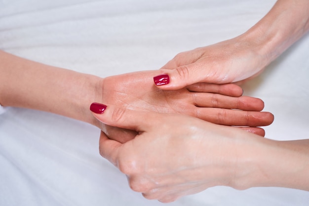 Profite de l'instant. Jeune beauté travaillant dans un salon tout en massant les mains pendant la session