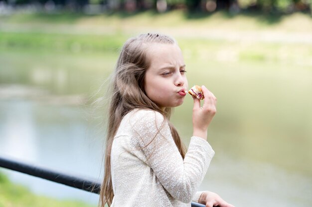 Profiter de chaque bouchée. Kid girl manger des biscuits. Concept de santé et de régime. Suivre un régime en comptant les calories. Rompre son régime pour les sucreries. Collation en plein air. Délicieuse collation saine aux biscuits. Biscuit sucré pur plaisir.