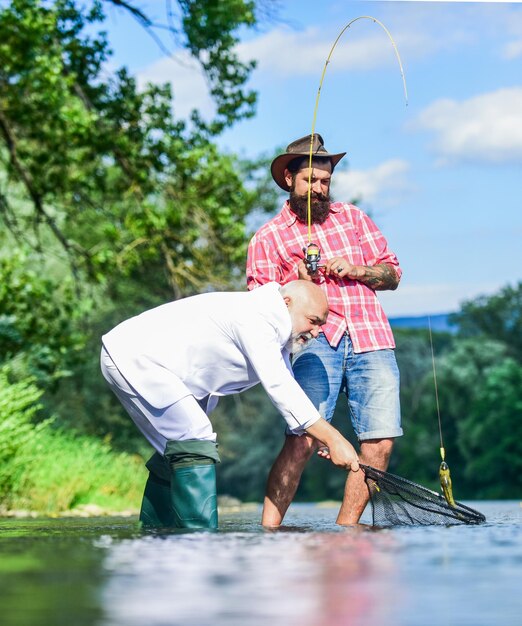 Profiter du temps ensemble poisson à la mouche passe-temps de la pêche à la retraite d'un homme d'affaires Deux amis masculins pêchant ensemble Attraper et pêcher des pêcheurs heureux amitié papa à la retraite et fils barbu mature