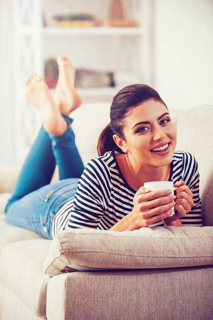 Profiter Du Temps Libre à La Maison. Belle Jeune Femme Tenant Une Tasse De Café Et Souriant