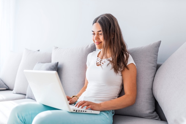 Profiter du temps à la maison. Belle jeune femme souriante travaillant sur lapto à la maison