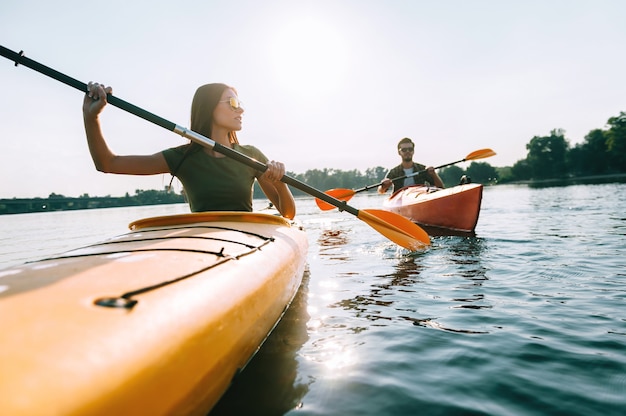 Profiter de la journée d'été sur le lac. Beau jeune couple kayak sur le lac ensemble et souriant