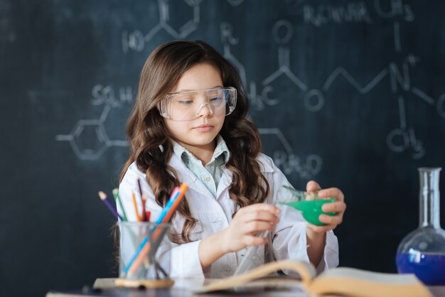 Profiter de ma future profession. Enfant habile et travailleur talentueux debout dans le laboratoire et bénéficiant d'une expérience de chimie tout en participant au projet scientifique et en explorant l'ampoule