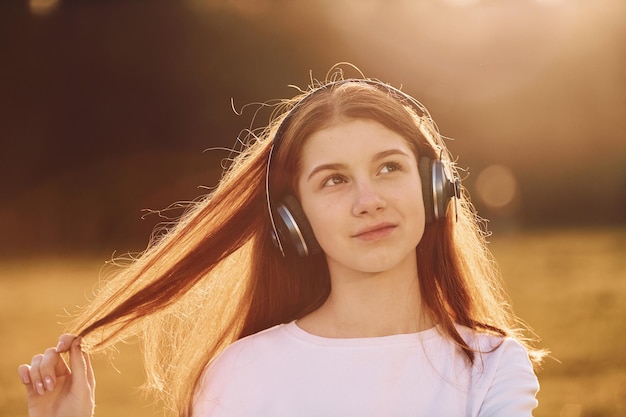 Profiter de la musique Jeune fille est sur le terrain pendant la journée ensoleillée ayant un bon week-end