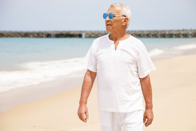 Profiter de la retraite. Heureux homme senior marchant sur la plage.