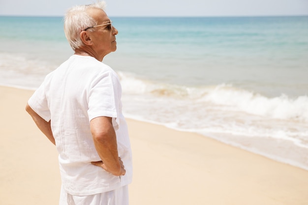 Profiter de la retraite. Heureux homme senior marchant sur la plage.