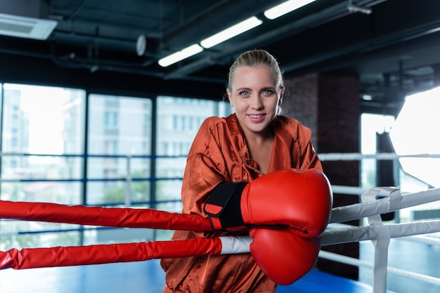 Profiter de son passe-temps. Belle femme d'affaires profitant de son passe-temps tout en boxe en ring dans une salle de sport spacieuse et moderne