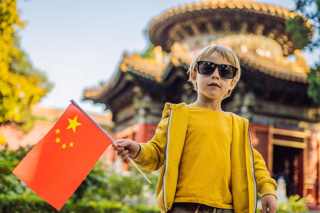 Profiter de vacances en Chine Jeune garçon avec le drapeau national chinois dans la Cité Interdite Voyage en Chine avec le concept d'enfants Transit sans visa 72 heures 144 heures en Chine