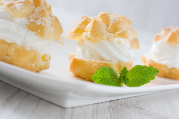 Profiteroles fraîches à la crème sur une table en bois blanc