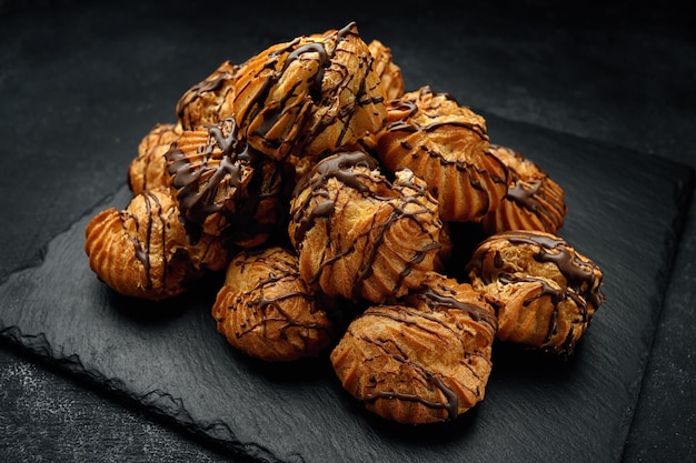 Profitrolls avec du chocolat sur fond sombre