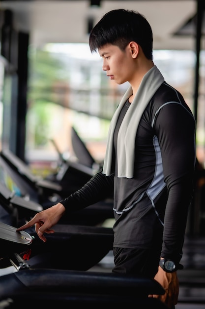 Programme de réglage de jeune bel homme en cours d'exécution pour un entraînement sain sur la bonne voie dans une salle de sport moderne,