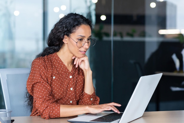 Programmeur développeur femme indienne réussie travaillant à l'intérieur d'un bureau moderne à l'aide d'un ordinateur portable au travail pour