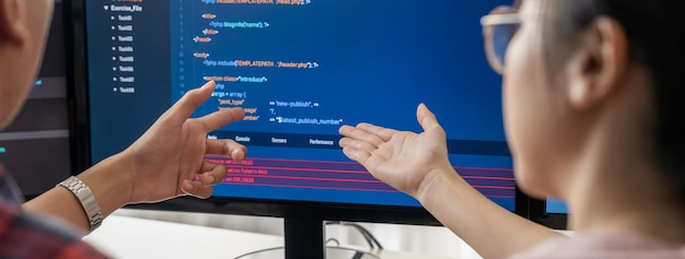 Une programmeuse explique en pointant le code affiché sur un ordinateur