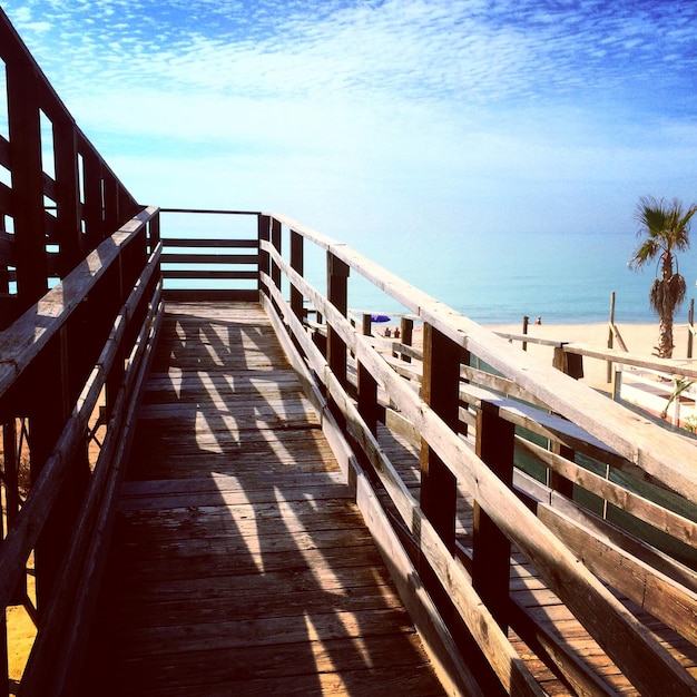 Photo une promenade en bois sur la plage contre un ciel nuageux.