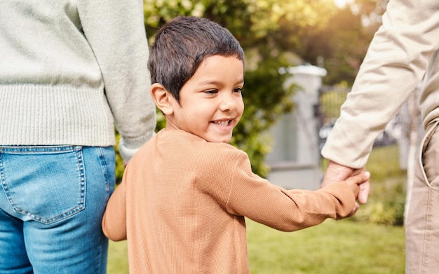 Promenade dans le parc pour enfants et main dans la main avec les parents en vacances aventure ou liberté dans la nature ensemble Jeune garçon enfant bonheur en plein air ou vacances avec un coup de main maman ou papa pour marcher au soleil