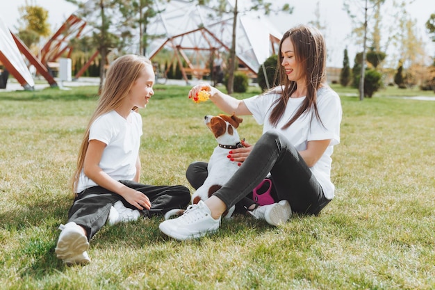 Promenade en famille dans le parc d'automne Divertissement en plein air Mère et fille promènent le chien par une chaude journée d'automne ensoleillée un enfant joue avec un jack Russell terrier dans le parc