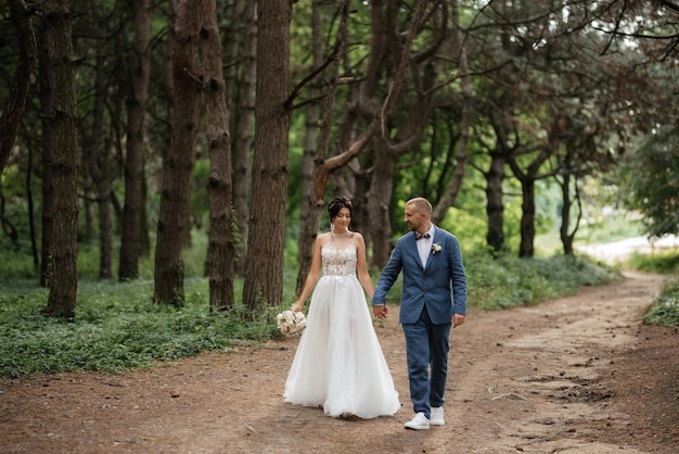 Promenade de mariage des mariés dans la forêt de feuillus en été