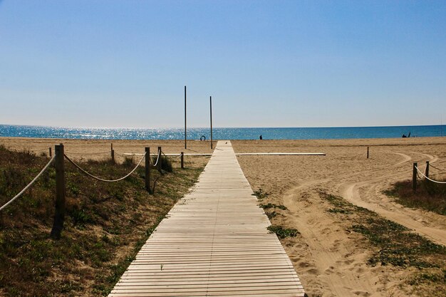 Une promenade menant à la plage contre un ciel dégagé.