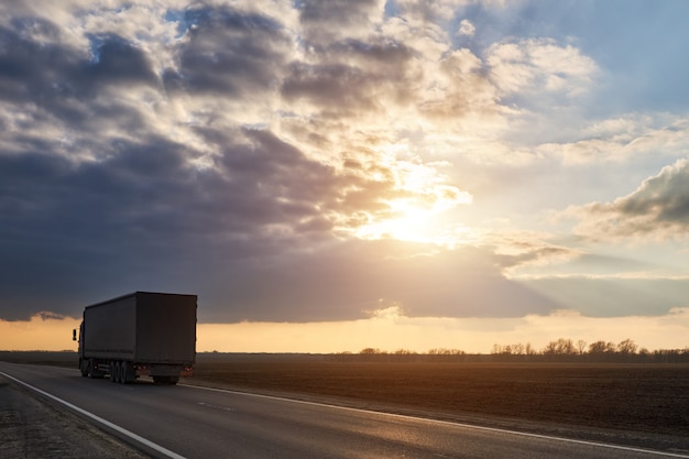 Promenades en camion sur l'autoroute dans le contexte de beaux nuages au coucher du soleil