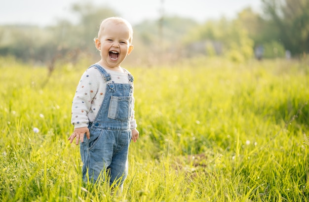 Promenades d'été pour enfants. L'enfant éprouve des émotions de joie dans la forêt sur un pré par une journée ensoleillée.