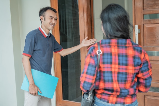 Promoteur immobilier masculin avec un geste de la main lors de l'invitation des clients à entrer dans la porte