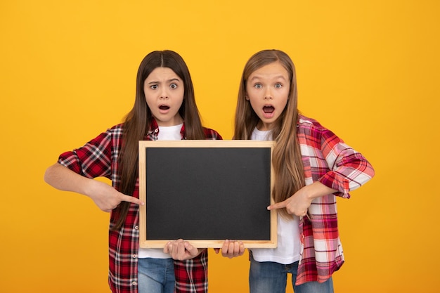 Promotion de l'offre éducative vente d'écoles filles choquées tenir la publicité des enfants au tableau noir retour à l'école enfants présentant des informations de nouveauté éducation de l'enfance espace de copie pour l'annonce