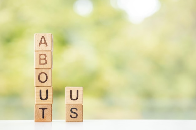 À propos de nous est écrit sur des cubes en bois sur un fond d'été vert Gros plan d'éléments en bois