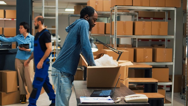 Propriétaire afro-américain prenant des produits dans des racks de stockage pour préparer la commande de marchandises dans l'entrepôt. Employé vendant des marchandises et travaillant sur le développement des affaires, la livraison au détail.