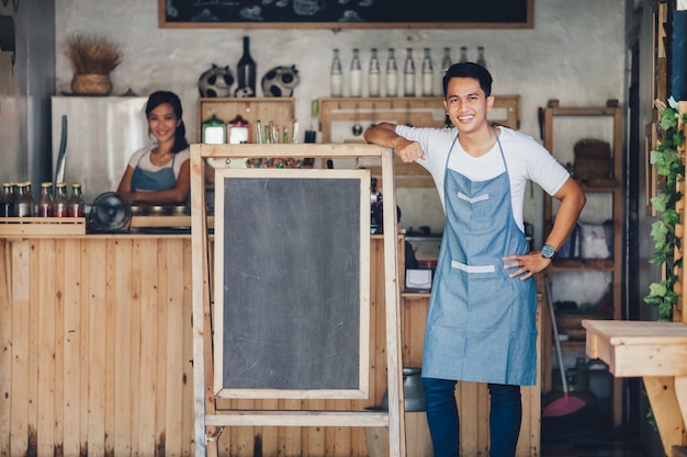 Propriétaire de café masculin asiatique avec tableau blanc