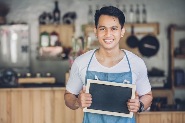 Propriétaire de café masculin asiatique avec tableau blanc