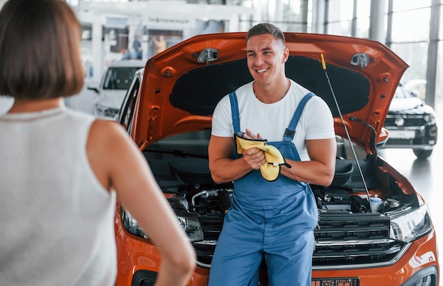 Photo propriétaire debout près de l'homme qui répare l'automobile à l'intérieur service professionnel