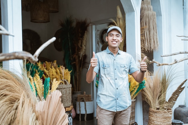 Propriétaire d'entreprise d'artisanat avec les pouces vers le haut en face de la boutique d'artisanat