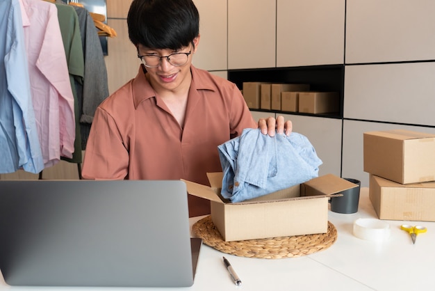 Propriétaire d'entreprise asiatique travaillant à la maison avec la boîte d'emballage de sa boutique en ligne se prépare à livrer des produits aux clients, concept de mode de vie de génération alpha