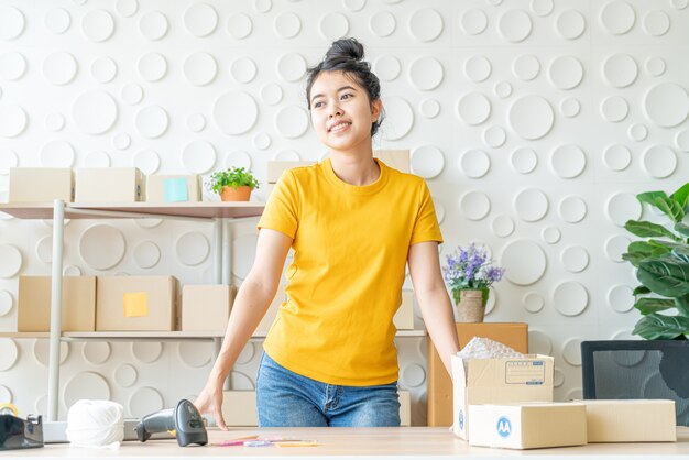 Propriétaire d'entreprise de femmes asiatiques travaillant à la maison avec boîte d'emballage sur le lieu de travail