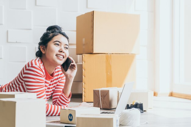 Propriétaire d'entreprise de femmes asiatiques travaillant à la maison avec boîte d'emballage sur le lieu de travail