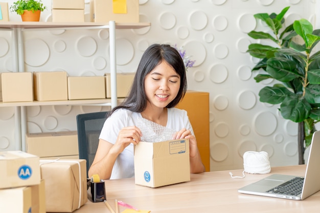 Propriétaire d'entreprise femmes asiatiques travaillant à la maison avec boîte d'emballage sur le lieu de travail