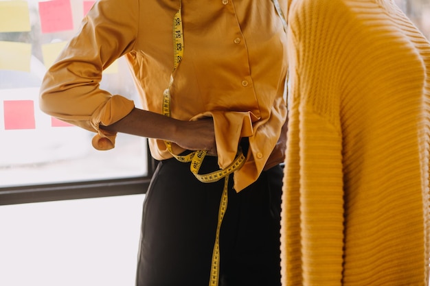 Propriétaire d'entreprise jeune designer de mode asiatique travaillant sur son designer dans la salle d'exposition Lifestyle tailleur élégant prenant des mesures sur un mannequin pour couper des tissus en studio Petite entreprise