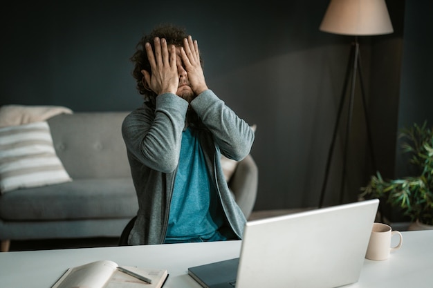 Le propriétaire d'une entreprise en ligne a mal aux yeux après une dure journée de travail avec un ordinateur qui se couvre les yeux ...