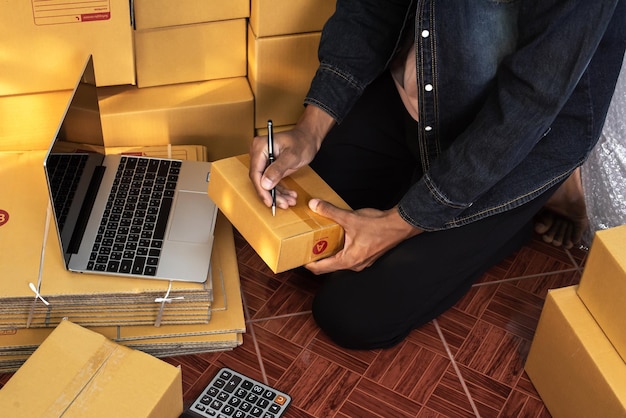 Propriétaire d'entreprise masculin travaillant à emballer la commande pour l'expédition à la boîte d'emballage du client pour la livraison