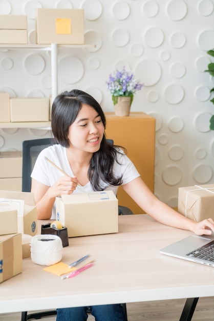 Propriétaire de petite entreprise, femme vérifiant le bon de commande dans un ordinateur portable