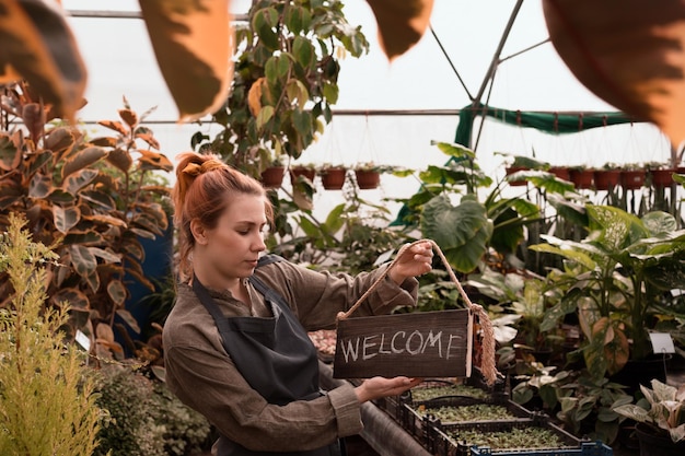 Propriétaire de petite entreprise avec panneau Bienvenue en anglais dans le magasin de jardinage