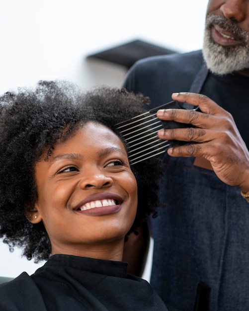 Photo propriétaire d'un salon de coiffure latino prenant soin d'un client