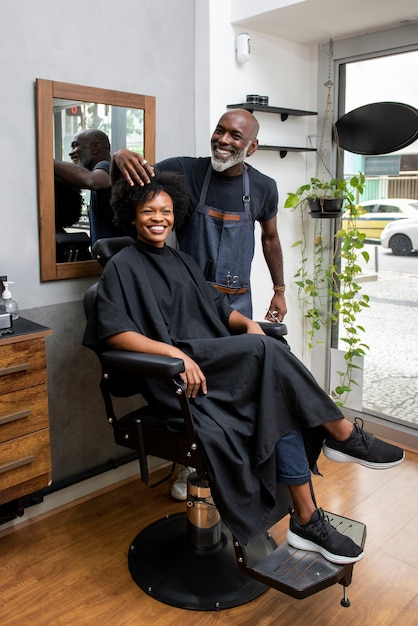 Photo propriétaire d'un salon de coiffure latino prenant soin d'un client